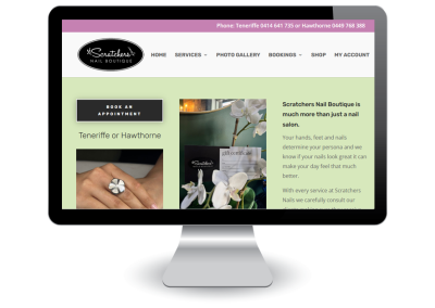 A computer monitor displays the Scratchers Nail Boutique website, featuring a booking button, contact numbers, images of manicured nails and flowers, and text describing the salon’s services.