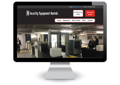 A computer monitor displays a website for Security Equipment Rentals, showing an image of security screening equipment in a parking garage with people nearby. The webpage includes contact details and navigation options.